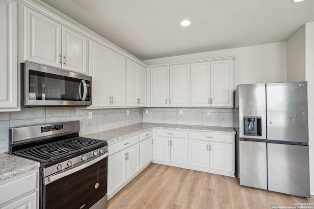 kitchen with appliances with stainless steel finishes, light wood-type flooring, and white cabinets