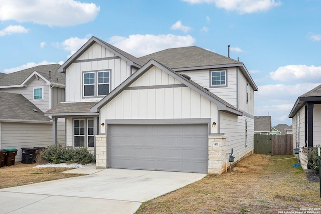 view of front of house with a shingled roof, concrete driveway, an attached garage, board and batten siding, and fence