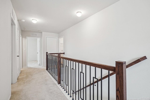 hall with light carpet, visible vents, an upstairs landing, baseboards, and attic access