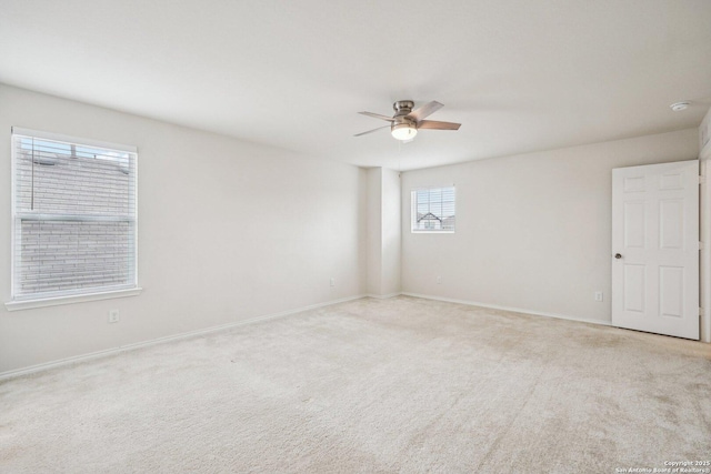 empty room featuring light carpet, baseboards, and a ceiling fan