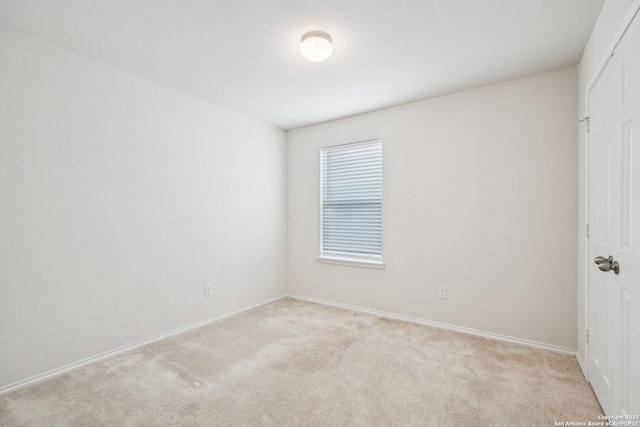 interior space with a closet, light colored carpet, and baseboards