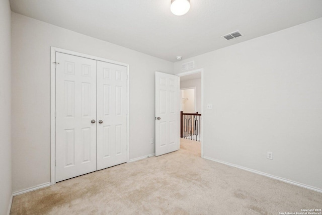 unfurnished bedroom with light carpet, a closet, visible vents, and baseboards