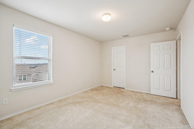 unfurnished bedroom featuring baseboards, visible vents, and light colored carpet