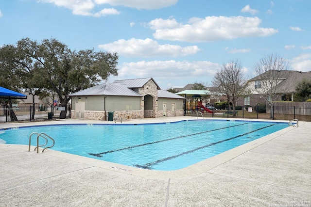 view of swimming pool featuring playground community and fence