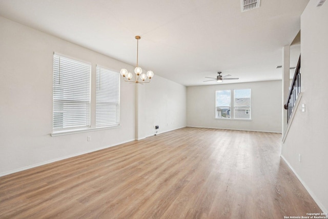 unfurnished room with light wood finished floors, visible vents, stairway, baseboards, and ceiling fan with notable chandelier