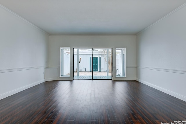 empty room with crown molding, baseboards, and dark wood-type flooring