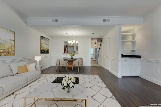 living area featuring a chandelier, visible vents, dark wood finished floors, and ornamental molding