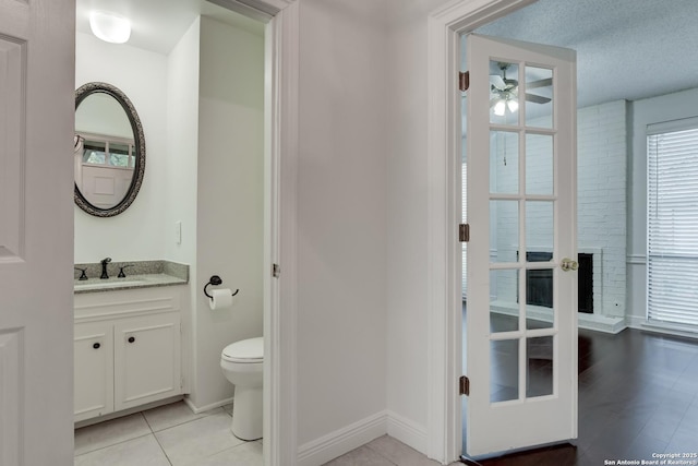 bathroom featuring toilet, a ceiling fan, vanity, a textured ceiling, and baseboards