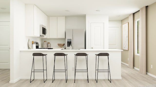 kitchen with a breakfast bar area, light wood-style flooring, stainless steel appliances, white cabinets, and light countertops