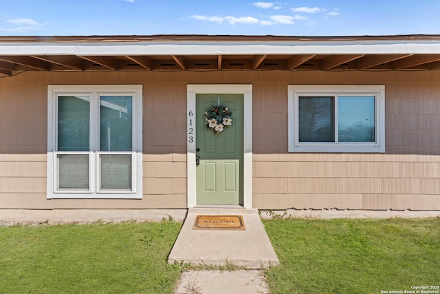 view of exterior entry featuring a lawn