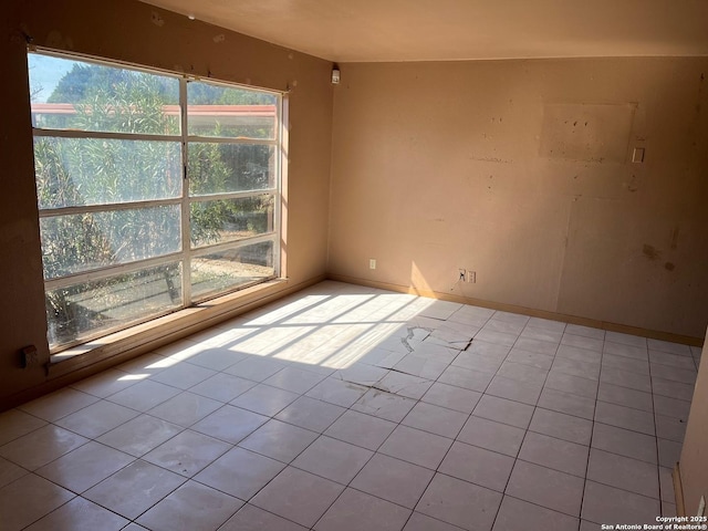 empty room with light tile patterned flooring and baseboards