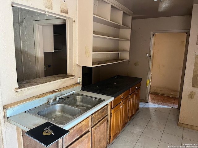 kitchen featuring brown cabinetry, light tile patterned flooring, and a sink