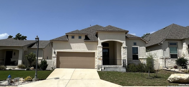 french country home featuring a garage, concrete driveway, stone siding, a front yard, and stucco siding