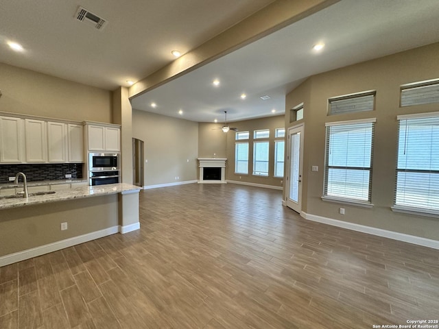 kitchen featuring visible vents, light stone counters, open floor plan, stainless steel appliances, and a sink