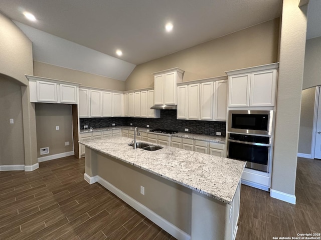 kitchen featuring white cabinets, an island with sink, built in microwave, stainless steel oven, and black gas stovetop