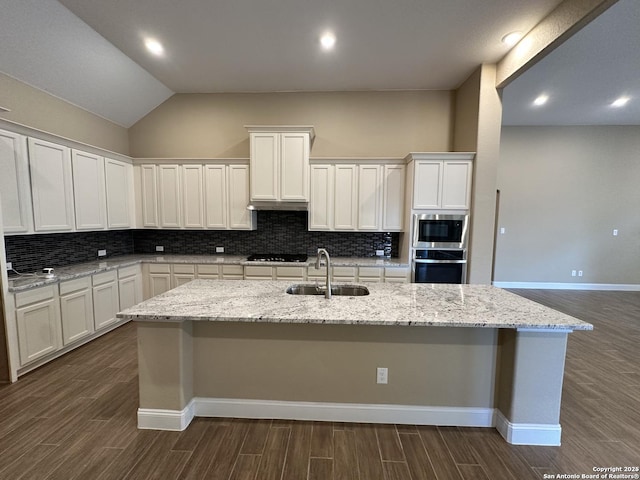 kitchen with appliances with stainless steel finishes, a kitchen island with sink, white cabinets, and a sink