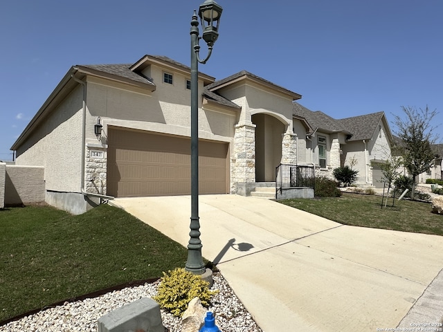 view of front of property with stucco siding, concrete driveway, an attached garage, a front yard, and stone siding