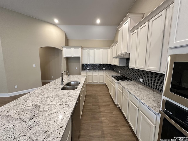 kitchen with light stone counters, stainless steel appliances, backsplash, white cabinets, and a sink