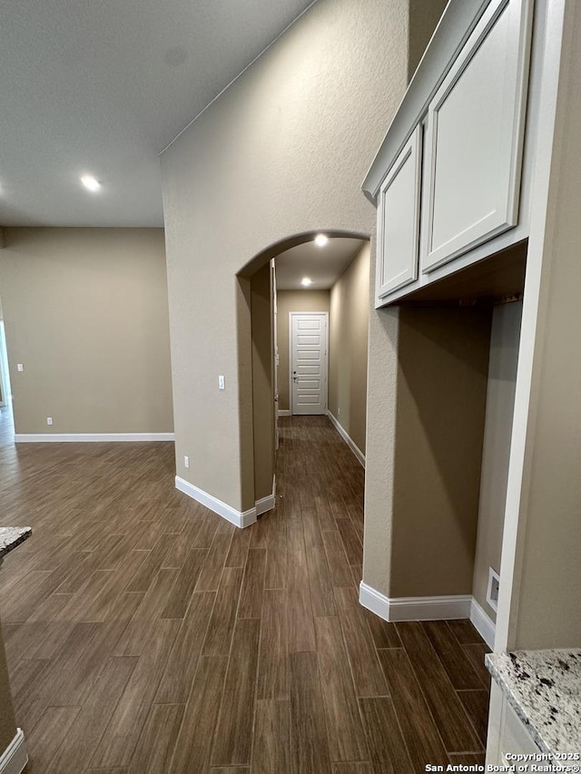 interior space with arched walkways, baseboards, and wood tiled floor