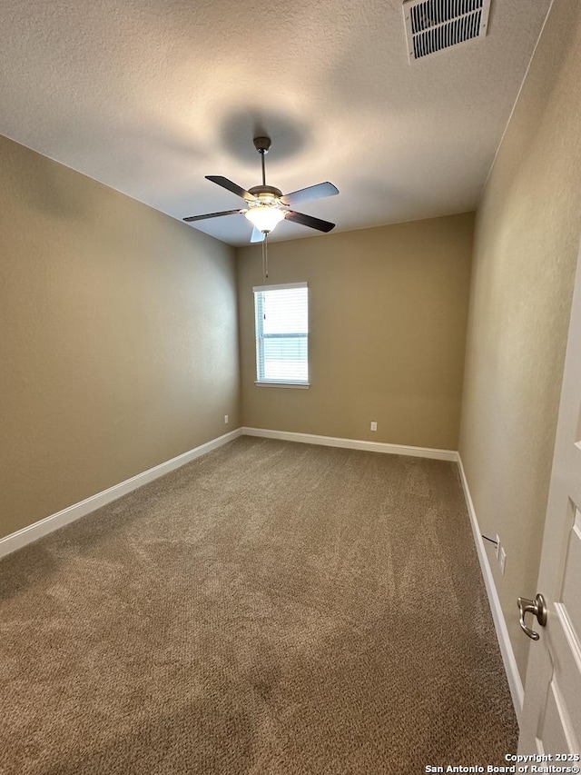 spare room with carpet floors, baseboards, visible vents, and a textured ceiling