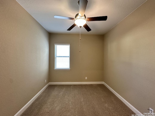 carpeted spare room with a ceiling fan and baseboards