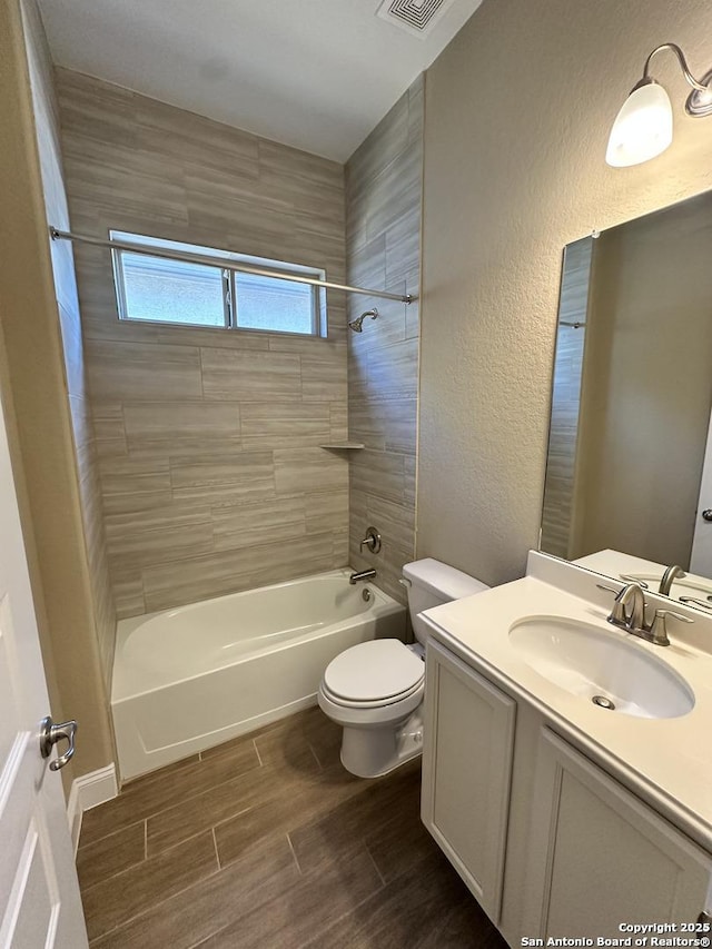 bathroom featuring a textured wall, toilet, vanity, washtub / shower combination, and wood finish floors