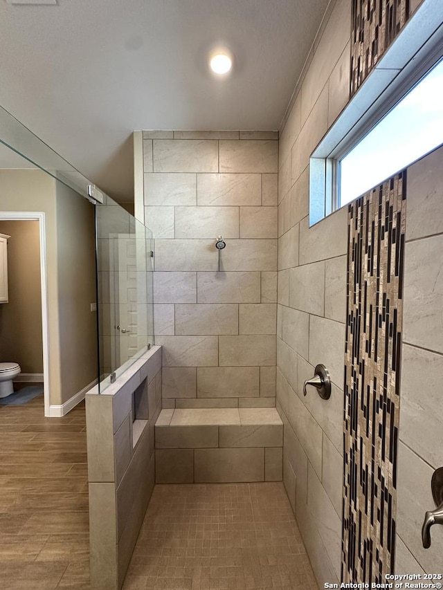 full bath with a walk in shower, wood finished floors, toilet, and baseboards