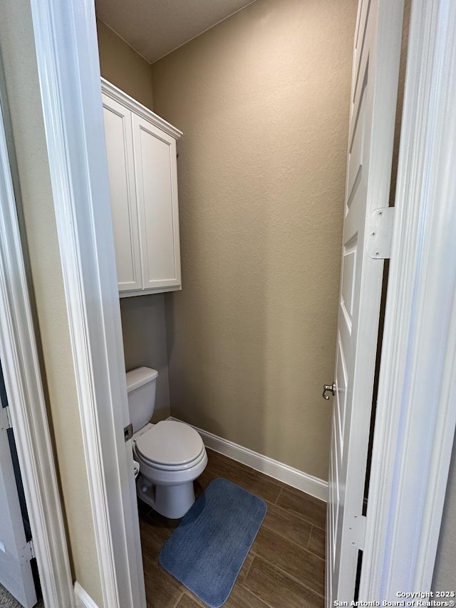 bathroom with baseboards, toilet, and wood finished floors