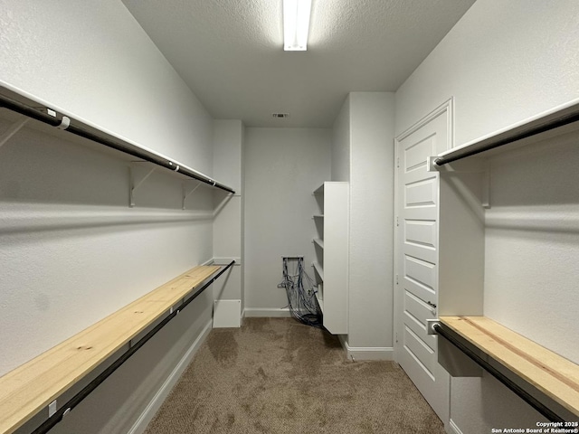 walk in closet with dark colored carpet