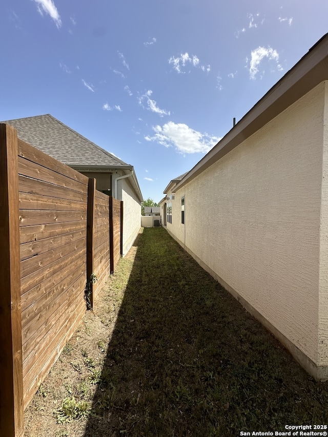 view of home's exterior featuring roof with shingles, fence, and stucco siding