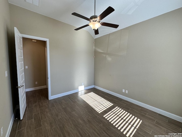 empty room with dark wood-style floors, visible vents, vaulted ceiling, and baseboards