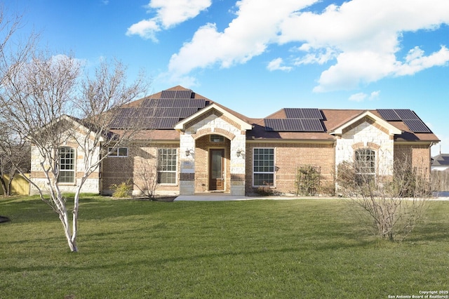 view of front of property with stone siding, a front lawn, solar panels, and brick siding