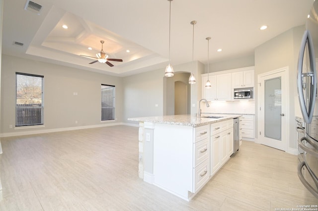 kitchen featuring stainless steel appliances, arched walkways, open floor plan, and a sink