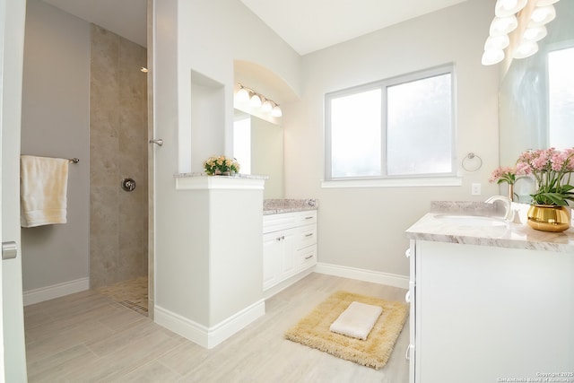 bathroom with two vanities, a sink, wood finished floors, baseboards, and walk in shower