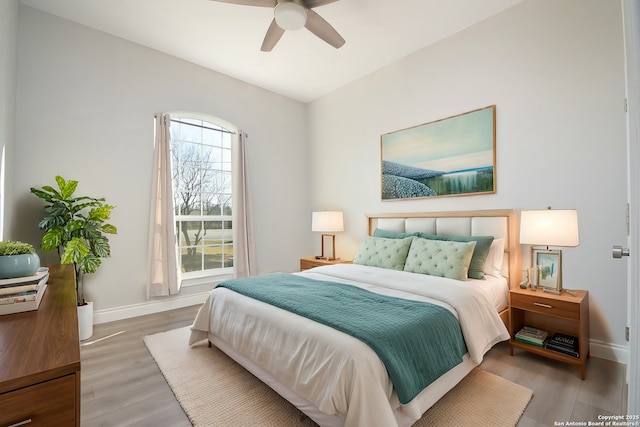 bedroom with ceiling fan, light wood-style flooring, and baseboards