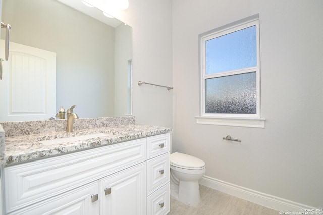 bathroom with toilet, vanity, and baseboards