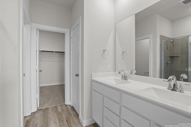 4338 Clarisse St, New Braunfels, TX 78130 - bathroom with a stall shower, wood finished floors, double vanity, a walk in closet, and baseboards