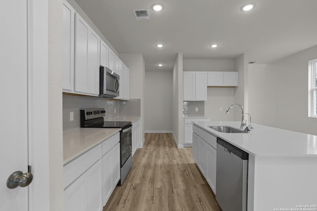 4338 Clarisse St, New Braunfels, TX 78130 - kitchen featuring stainless steel appliances, a sink, decorative backsplash, light wood-style floors, and white cabinets