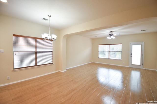 unfurnished room with ceiling fan with notable chandelier, light wood finished floors, visible vents, and baseboards