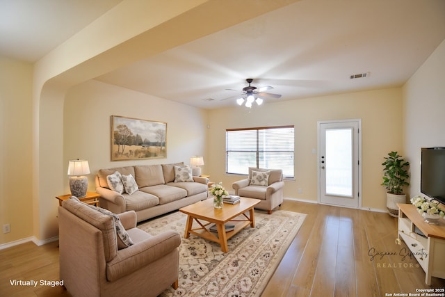 living room featuring light wood finished floors, baseboards, visible vents, and ceiling fan