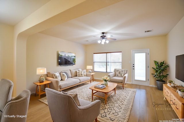 living room featuring ceiling fan, light wood-style flooring, visible vents, and baseboards