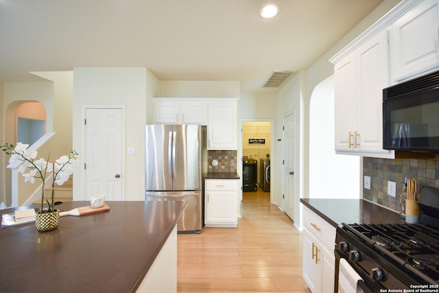 kitchen featuring black appliances, white cabinets, and washer and dryer