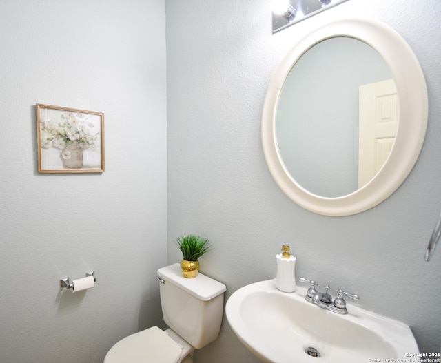 bathroom featuring a textured wall, a sink, and toilet