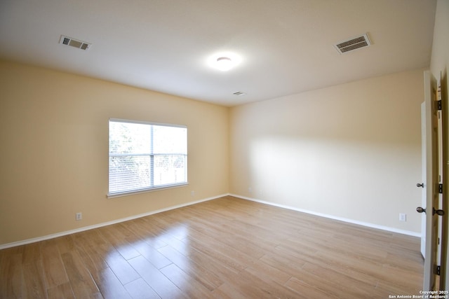 spare room featuring light wood-type flooring, baseboards, and visible vents