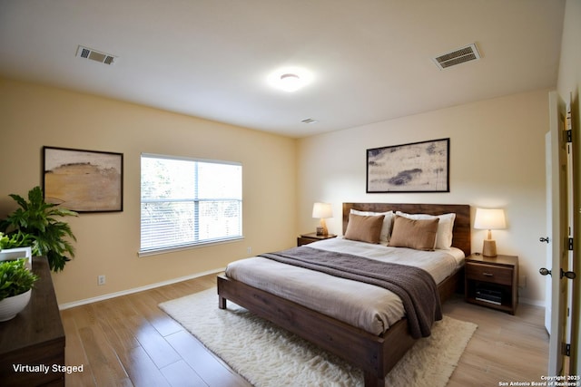 bedroom with light wood-type flooring, visible vents, and baseboards