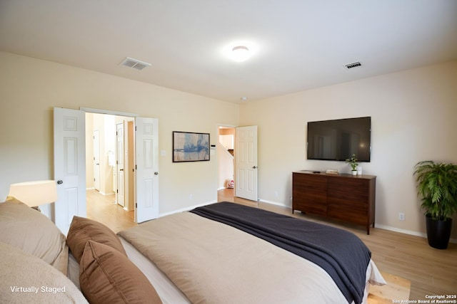 bedroom featuring light wood-style flooring, visible vents, and baseboards