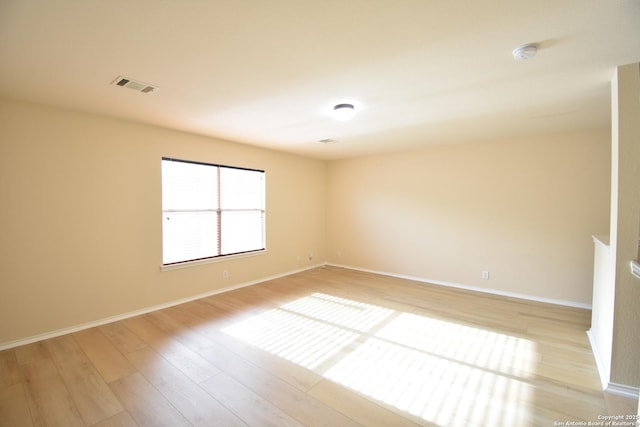 unfurnished room with baseboards, visible vents, and light wood-style floors