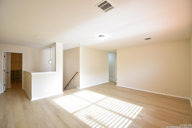 spare room with light wood-type flooring, baseboards, and visible vents