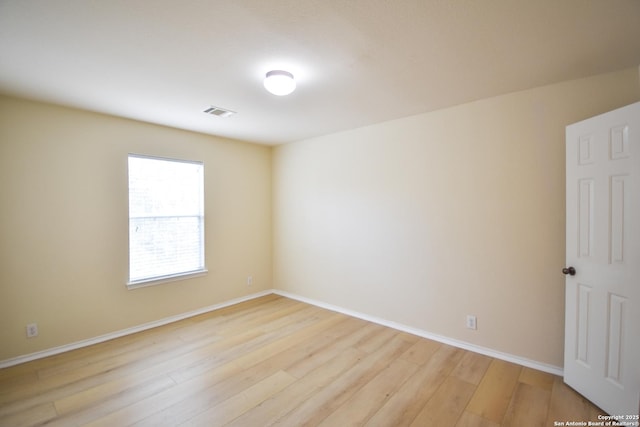 unfurnished room featuring light wood-style floors, visible vents, and baseboards