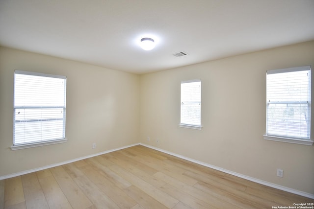 unfurnished room with light wood-type flooring, visible vents, and baseboards